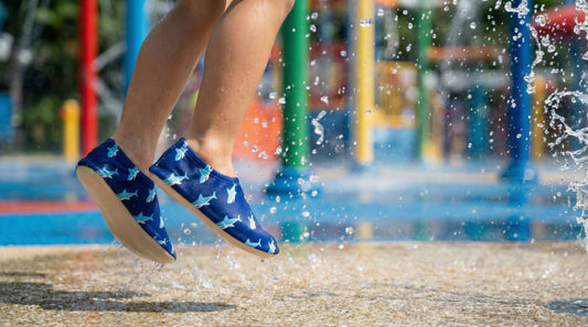 child jumping in a waterpark wearing blue non-slip water shoes with shark pattern