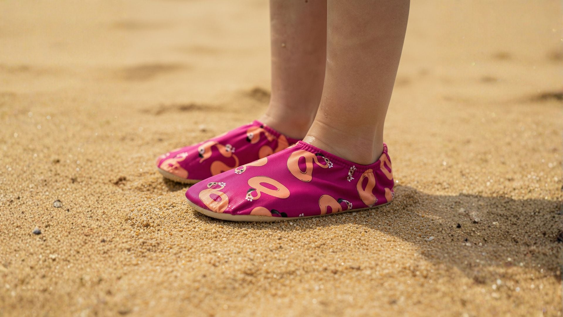 Pink non-slip water socks with peach flamingo design on a sandy Singapore beach.