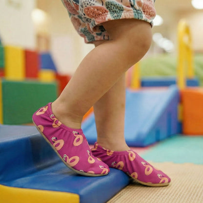 Child wearing pink non-slip socks with flamingo patterns on a colorful playground.