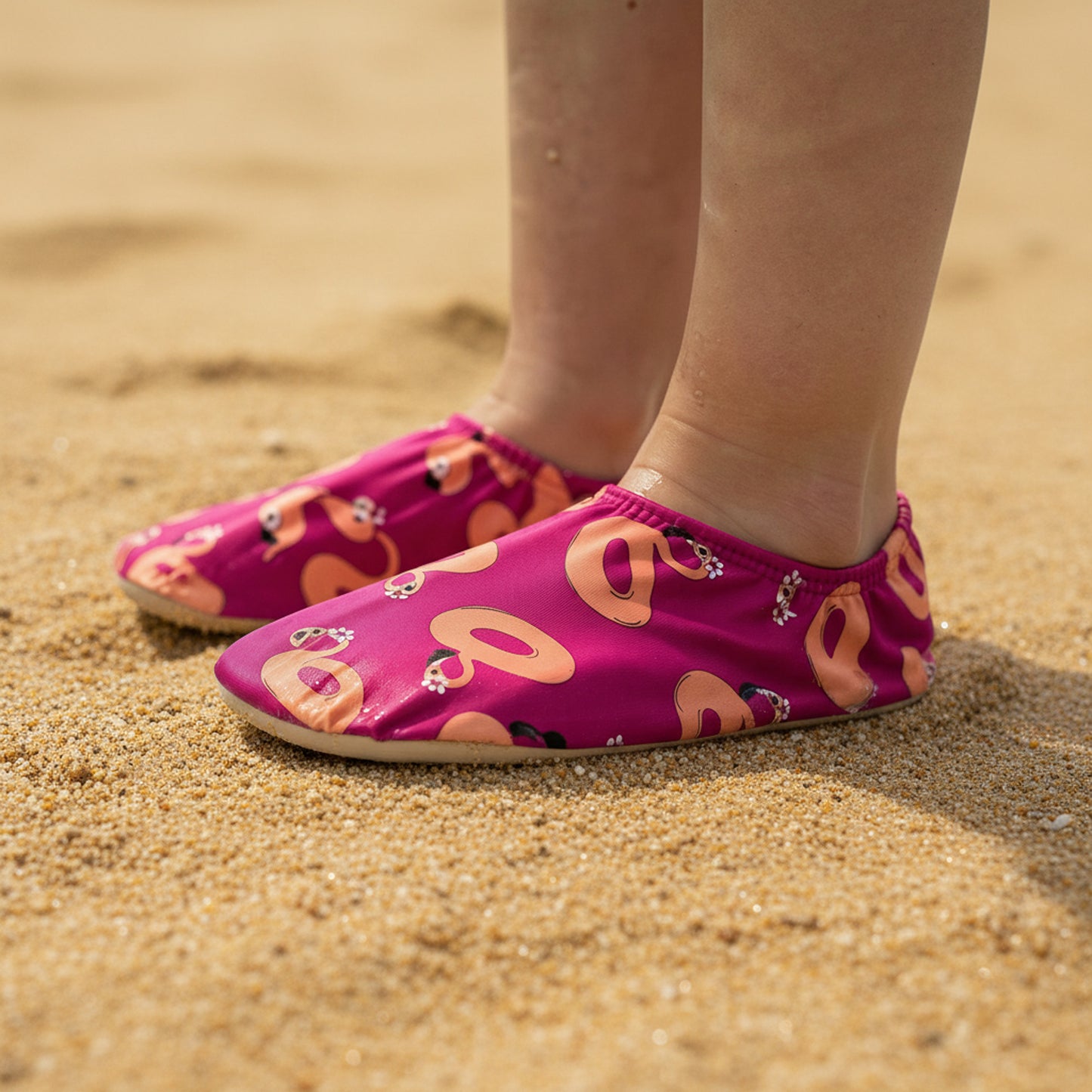 Pink non-slip water socks with peach flamingo design on a sandy Sentosa beach.