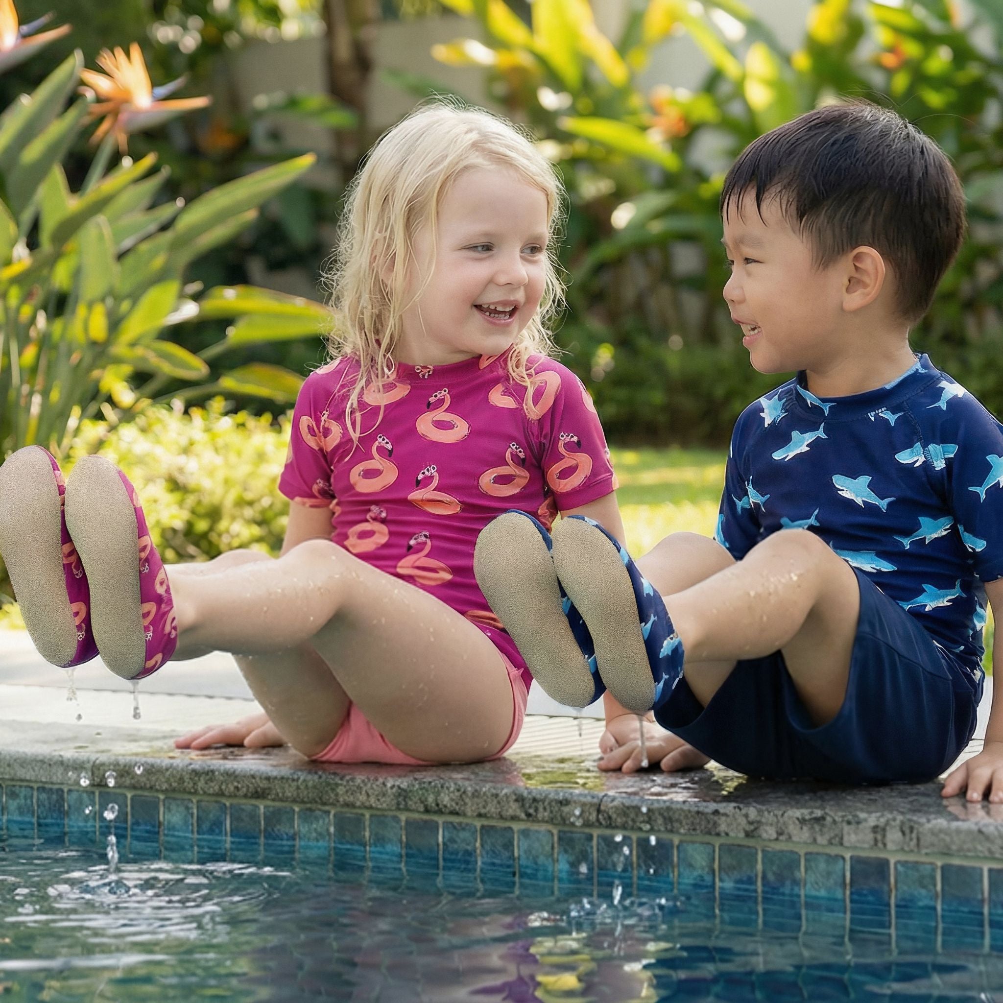 Two children sitting by a Singapore pool with a garden background, wearing non-slip water socks