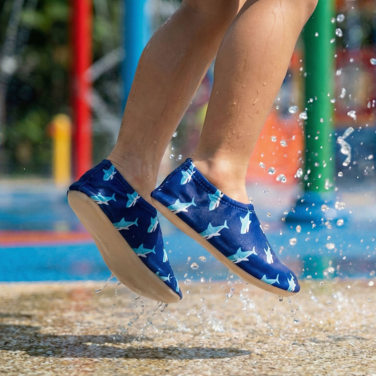 Blue shark-patterned non-slip water socks being worn by a child jumping into water at a Singapore waterpark.