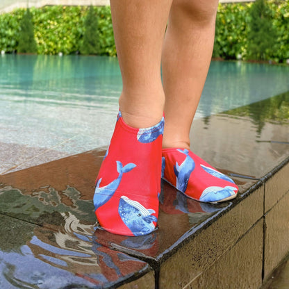 Red and blue whale-patterned non-slip water socks worn by a child by a Singapore pool.